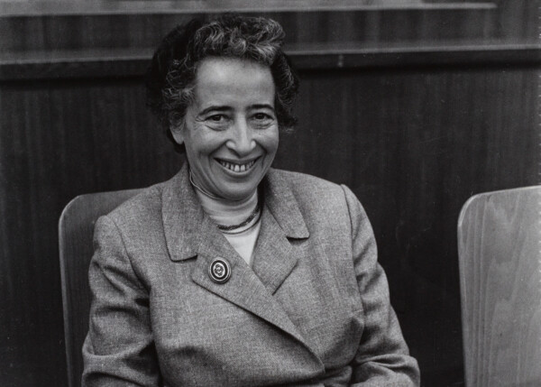 Hannah Arendt, fotograferet i 1958 siddende i en stol, smiler til kameraet