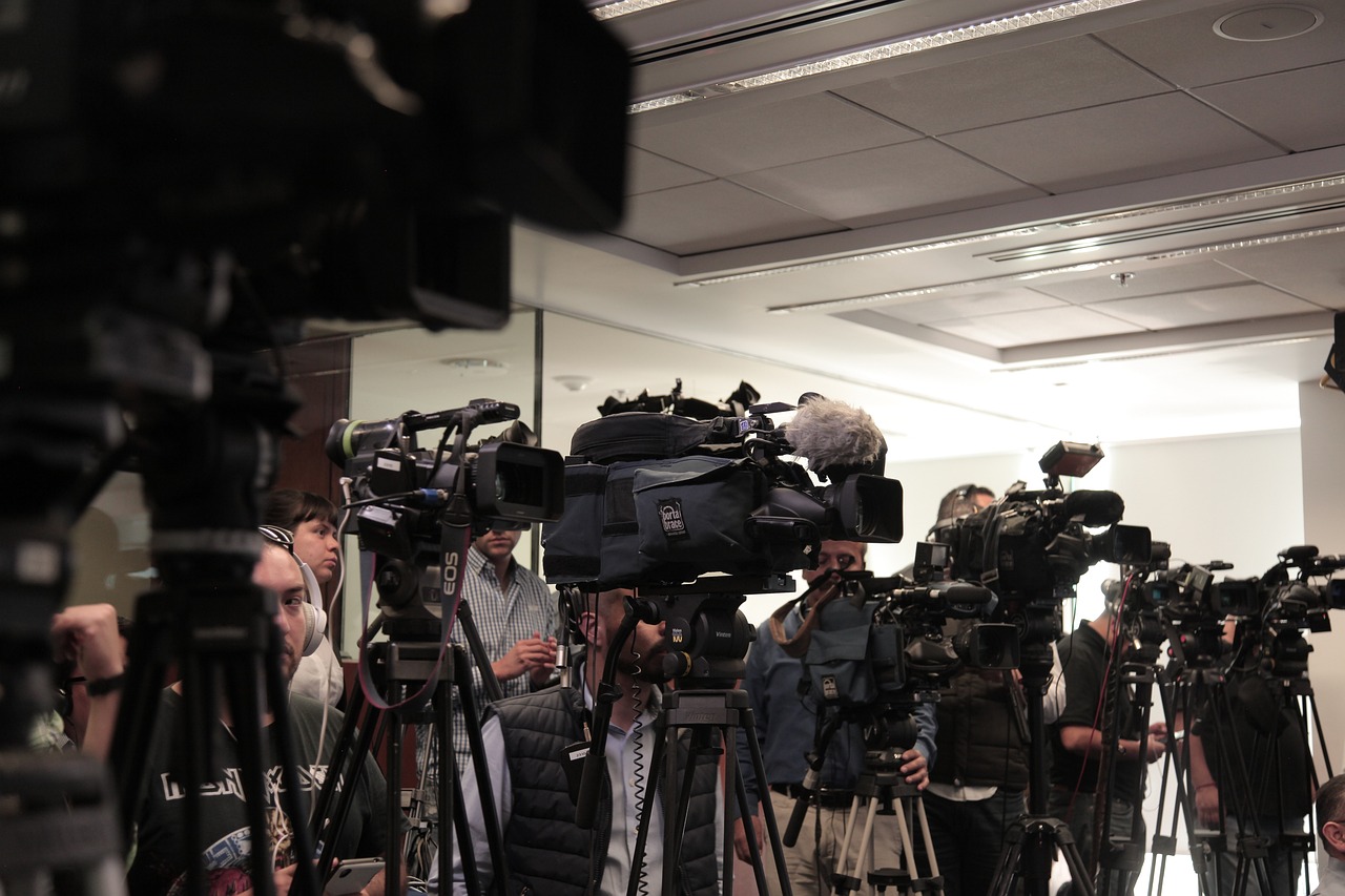 En gruppe af fotografer står side om side og filmer et pressemøde