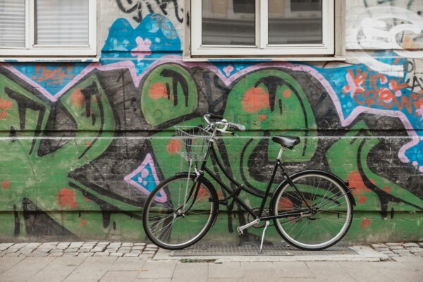 En cykel er parkeret op ad en væg med grøn grafitti på Nørrebro